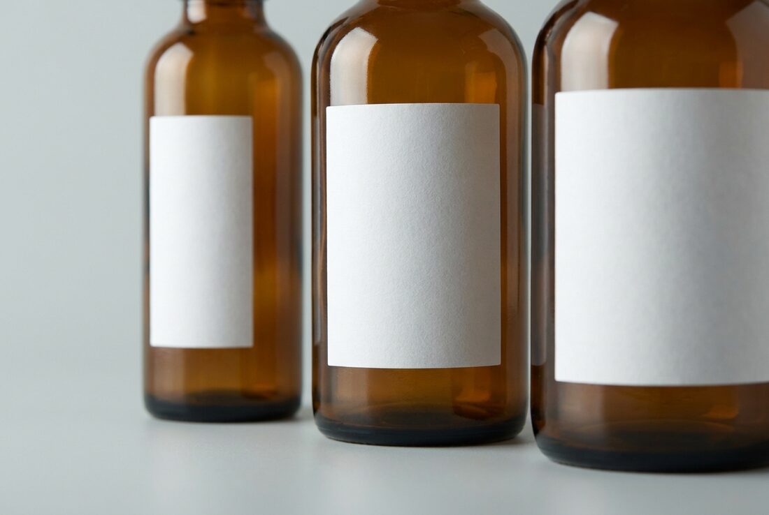Three amber glass bottles carrying plain unprinted white labels